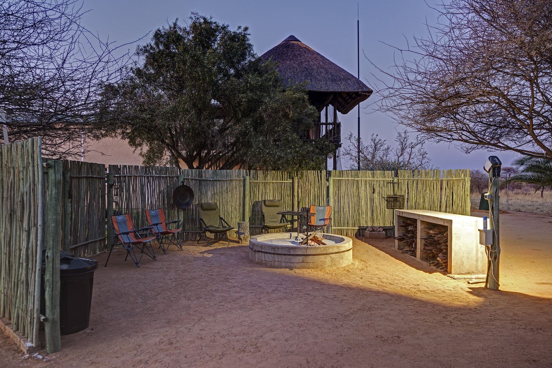 The fire pit lit at dusk beside the guest rooms