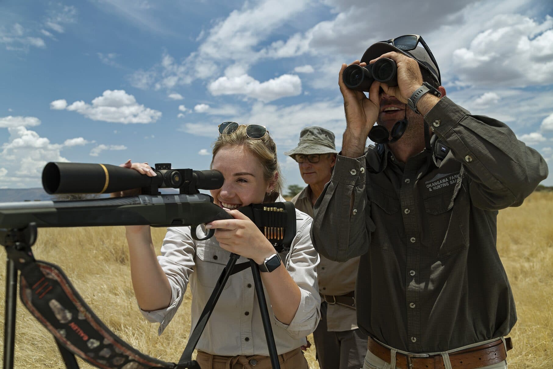 A guest aims from the shooting sticks while Andrew Campbell searches the plains with his binoculars