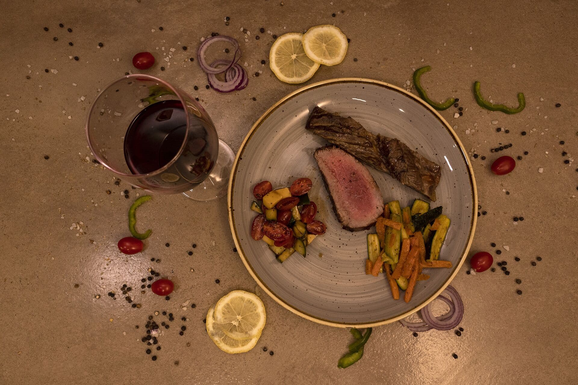 Game steak with vegetables and a glass of red wine